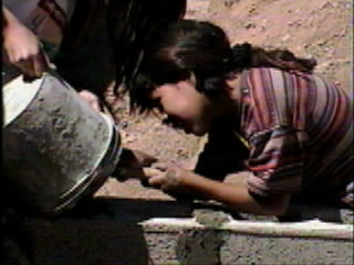 Girl scraping the bucket of cement